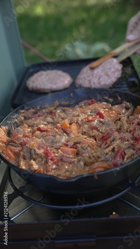 Person cooking beef stroganoff and hamburgers on camping stove