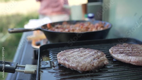 Sizzling beef burgers cooking on outdoor camping stove