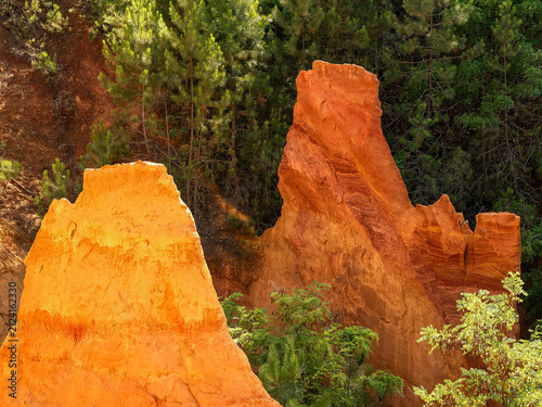 Two rocky outcrops, one of yellow ochre and one of red ochre, rise up from the vegetation