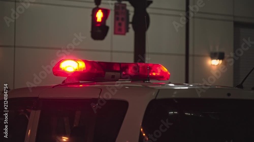 夜の交差点に停車するランプをつけたパトカー