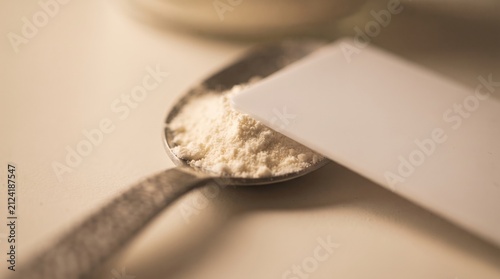 A silver spoon holds a fine white powder while a plastic card lies nearby, reflecting soft kitchen light. The scene captures the essence of baking, perfect for culinary enthusiasts.