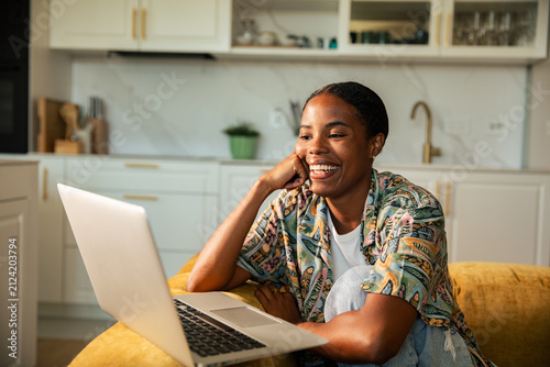 Smiling woman working on laptop at home kitchen