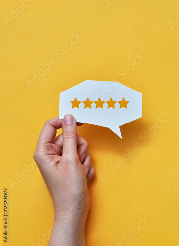 Canvastavla Hand holding five star rating speech bubble on yellow background