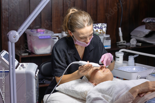 Professional cosmetologist performs an ultrasonic skin scrubber facial treatment, deeply cleansing pores and exfoliating the skin during an advanced skincare procedure in a beauty clinic.