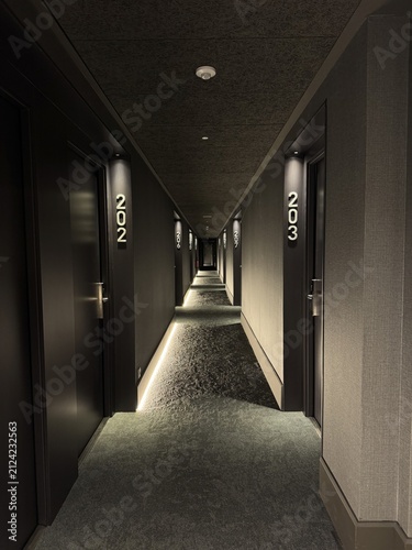 Fotografía A long dark hotel corridor recedes toward a central vanishing point, lined with