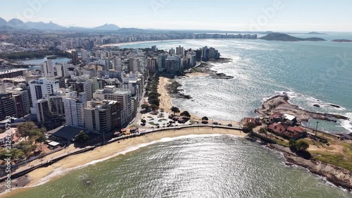 Panoramic aerial drone view of Guarapari, Espírito Santo, Brazil, with tropical beaches, turquoise Atlantic Ocean, urban coastline, rocky shores and mountains in the background.	
