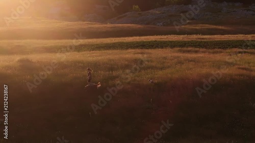 Drone Following a Woman Walking with Her Dog at Golden Sunset