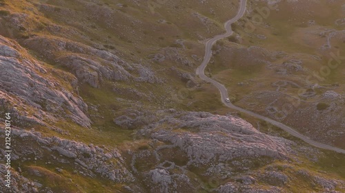 Drone Flying Above a Mountain Road at Sunset with a Moving Car