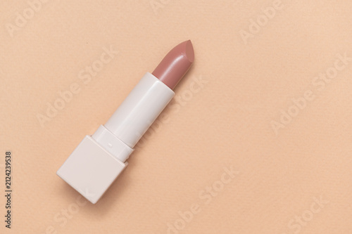 Beige lipstick in a beige container. On a beige background. Space for text.