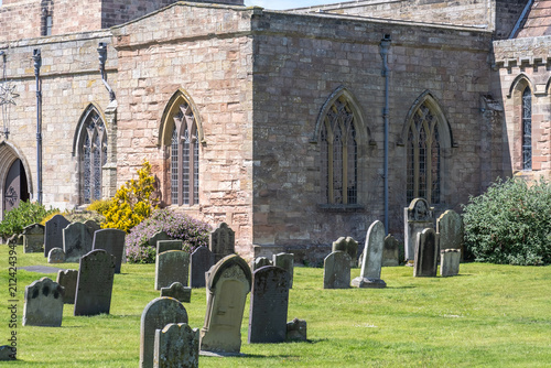 Headstones and gravestones in a churchyard, weathered stone memorials set among grass, reflecting history, remembrance, and quiet atmosphere.