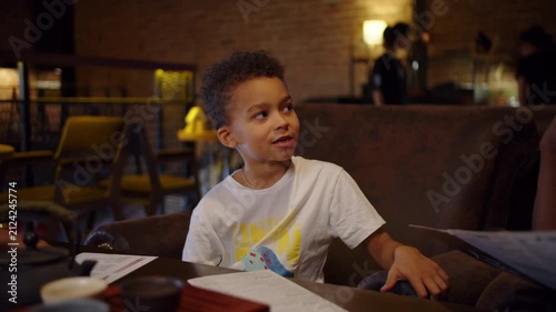 Young boy sitting in cozy cafe and looking away