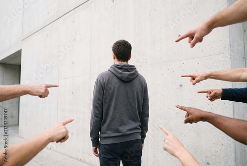 Man facing social stigma as multiple hands point accusatorily
