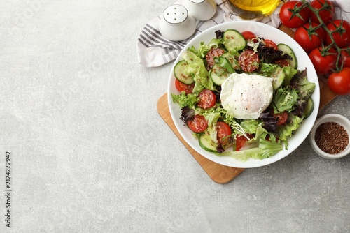 Fotografie Delicious vegetable salad with poached egg in bowl and ingredients on gray textured table, flat lay