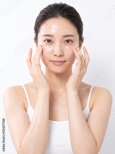 Woman Applying Moisturizing Cream on Face with Soft Expression