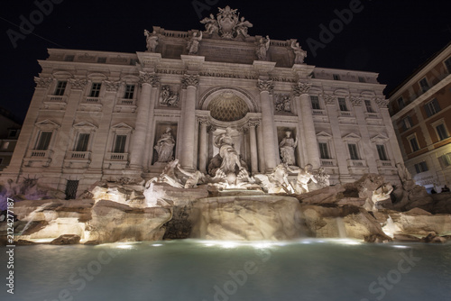View of the illuminated Trevi Fountain at night with flowing water in Rome, Lazio, Italy.