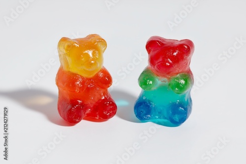 Gummy bears stand side by side on white ground.