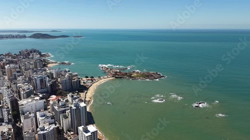 Panoramic aerial drone view of Guarapari, Espírito Santo, Brazil, with tropical beaches, turquoise Atlantic Ocean, urban coastline, rocky shores and mountains in the background.	
