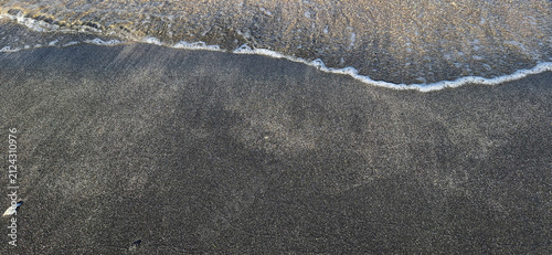 Принти на полотні Aerial top-down view of dark pebble beach shoreline with white sea foam wave rec