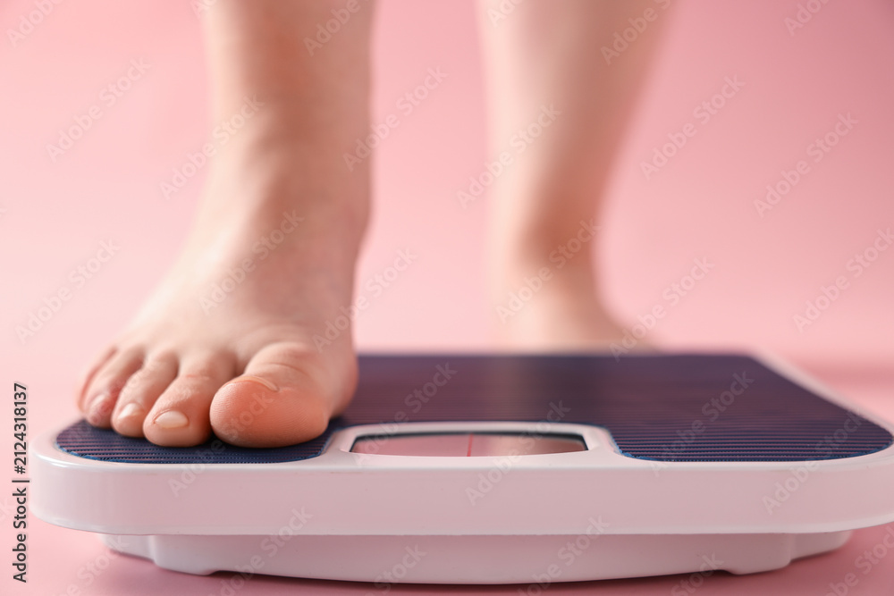 Fototapeta premium Overweight woman on scale against pink background, closeup
