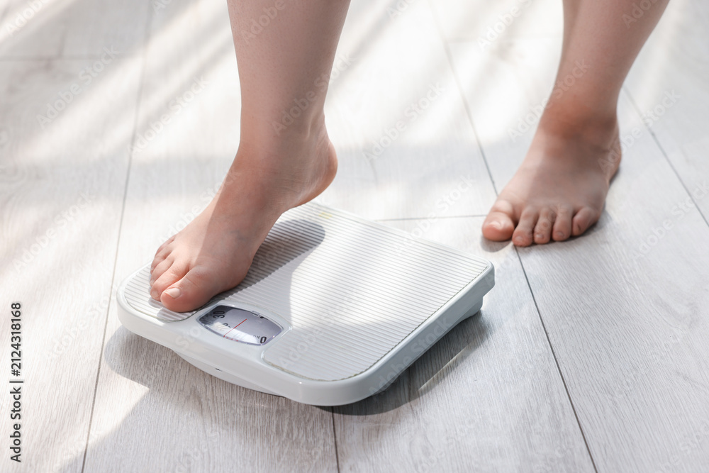 Fototapeta premium Overweight woman on scale at home, closeup