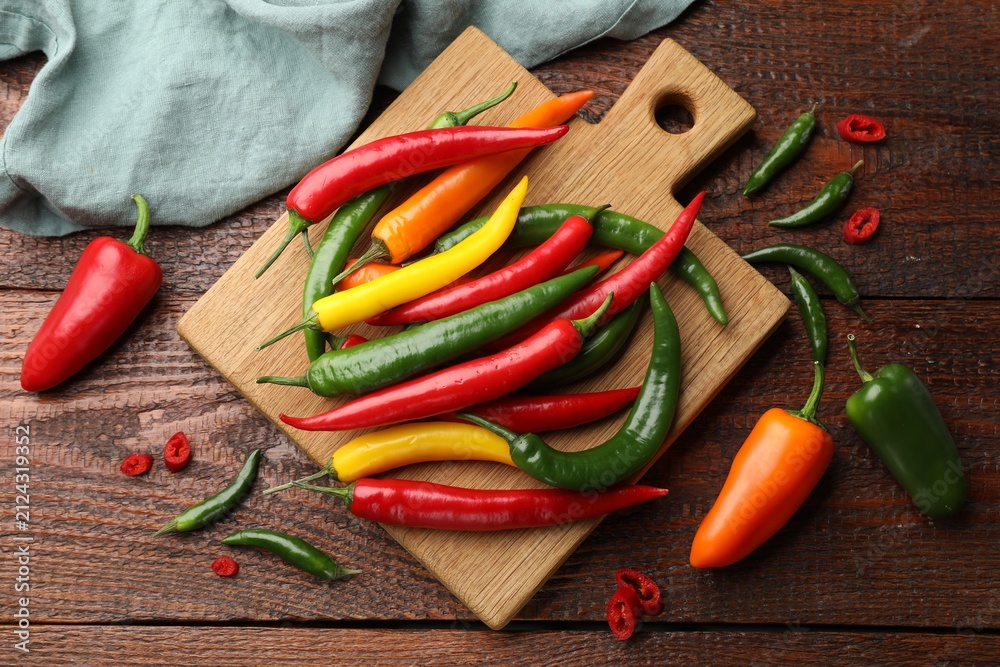 Fototapeta premium Fresh colorful chili peppers on wooden table, flat lay