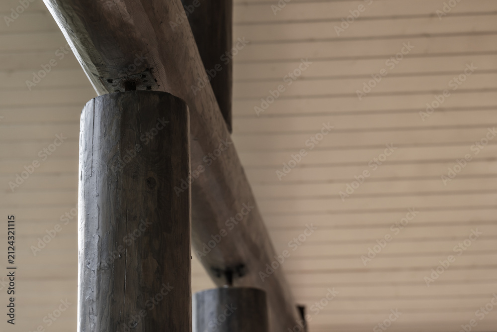 Fototapeta premium Close-up view of a rustic wooden railing and support posts set against a painted planked ceiling, showcasing natural grain, texture and architectural detail in a cabin or lodge interior