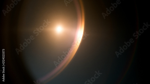 Warm golden anamorphic lens flare glowing on camera glass. Cinematic orange light leak overlay on dark background or visual effects overlays, filmic lighting, and cinematic video post-production