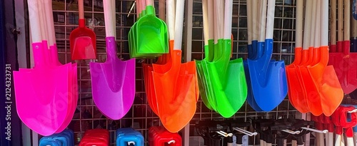 Colorful plastic garden shovels hung with wooden handles on retail display rack