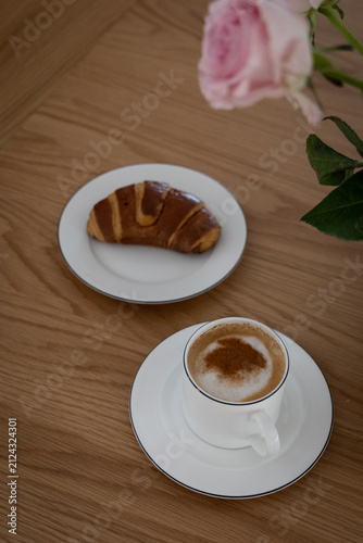 Cozy Morning Breakfast with Cappuccino, Croissant and Pink Roses on Wooden Table