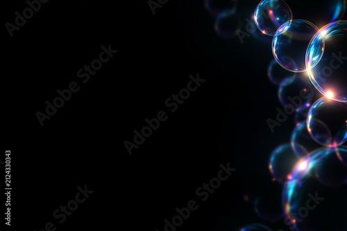 Iridescent soap bubbles border on black background. Glowing transparent colorful spheres frame. Copy space for text, creating a versatile background for graphic design.