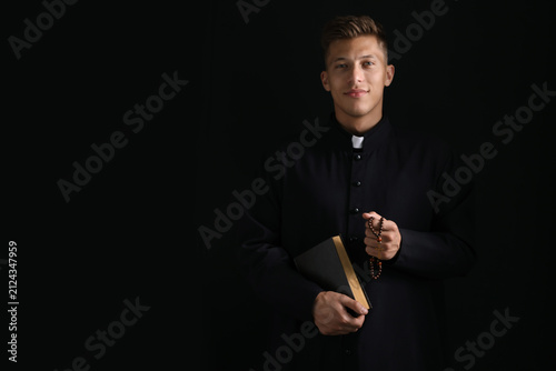 Fotografie Portrait of priest with rosary and Holy Bible on black background