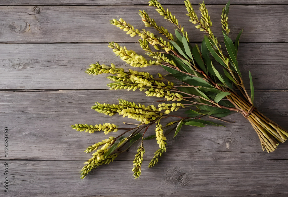 Fototapeta premium Bundle of yellow flowering acacia branches with green leaves on a rustic wooden background, natural decor concept, this natural arrangement provides a charming decor element
