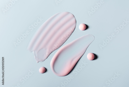 Pink cosmetic smears of cream texture on pastel blue background. Skin care