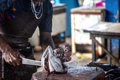 Bild auf Leinwand Fishmonger Cutting Fresh Fish on Wooden Block at Market