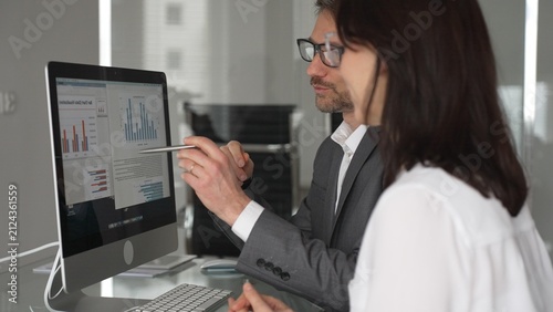 Obraz na plátně Business professionals collaborating and discussing information on a computer screen during a meeting in an office setting, actively engaging in teamwork and strategic planning