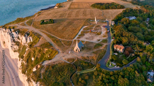 Aerial view of an isolated house surrounded by trees on a green coastal hillside