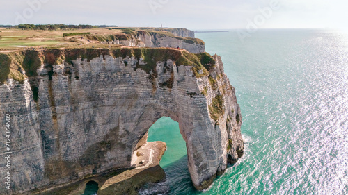 Фотография Top down aerial view of a cliff headland with a natural arch surrounded by turqu