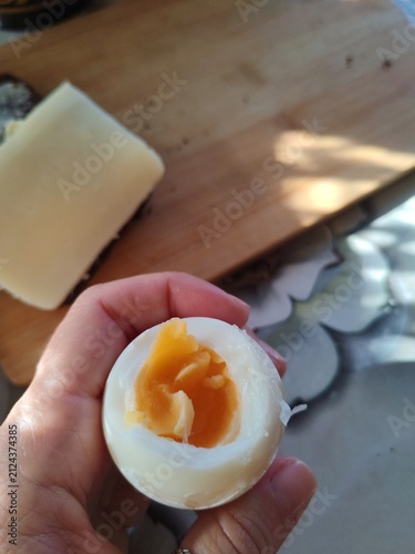 Hard-boiled egg with bright yellow yolk on a rustic breakfast table at a countryside veranda at morning.Cheese is at background 