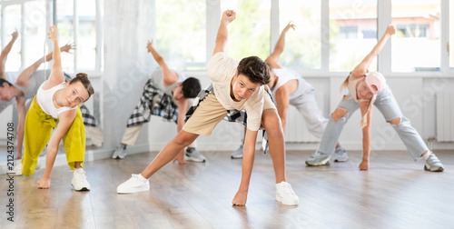Quadro su tela During rehearsal workout, teenage guy dances hip hop with friends against background of large mirror, window