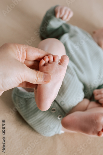  Softly cupped infant toes within caring adult palms. Delicate baby hand cradled tenderly bycexperienced adult hands in soft lighting. Gentle parental contact creates safe haven. 