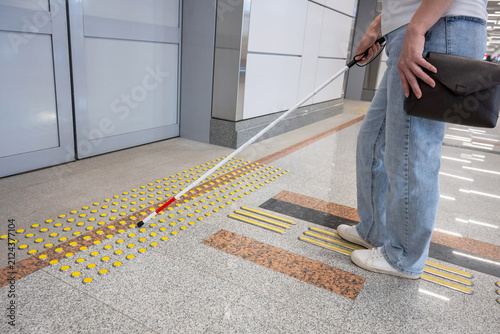 A blind woman waits for a train on the subway.
