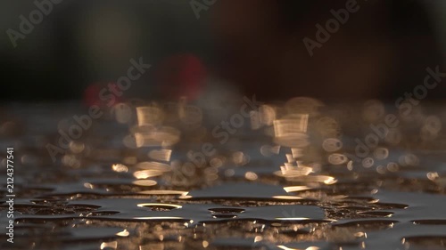 Sunset sunlight shines on transparent raindrops on a wooden surface, blurry background