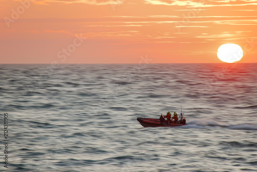 Bild auf Leinwand Sauveteurs en mer et coucher de soleil