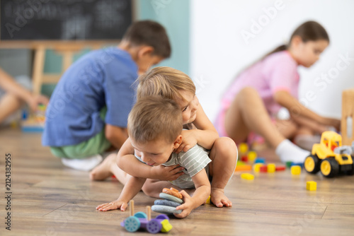 фотографія Happy baby boy and girl enjoying playtime while other children playing in backgr