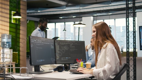 Foto Young female programmer writes code and develops machine learning APIs, troubleshooting software errors and faults with artificial intelligence while working on a computer in a startup office