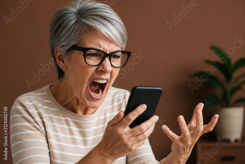 Frustrated middle-aged woman yelling on phone during a heated call at home, expressive emotion and stress captured in candid portrait