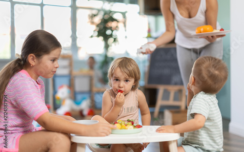 фотографія Group of little boys and girls have lunch together at modern childcare center