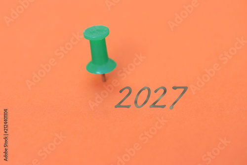 Eine Heftzwecke und ein Blatt Papier mit der Jahreszahl 2027
