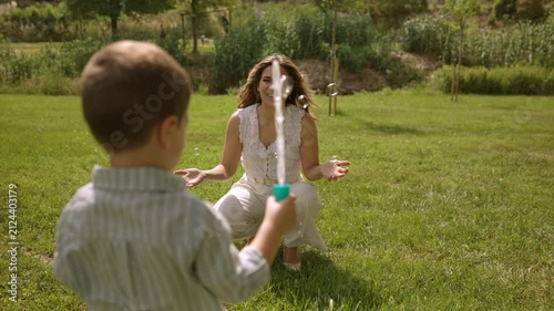 Mother and son blowing soap bubbles in a sunny park