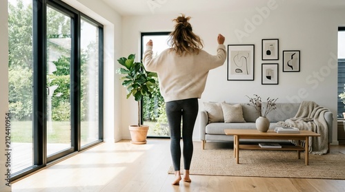 Energetic woman dances happily in her modern, sunlit living room, embracing joy and freedom at home